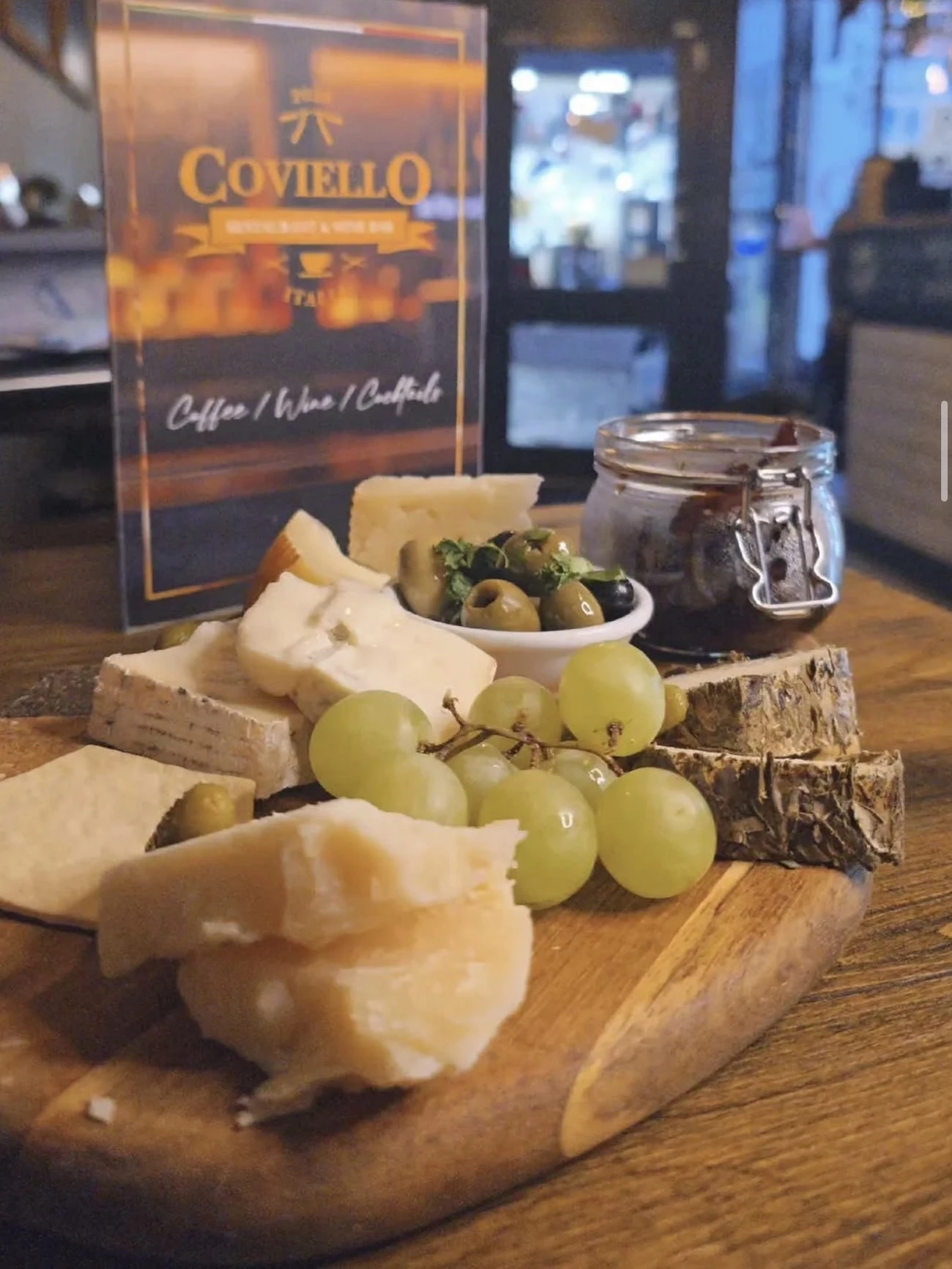 An Italian sharing board of cheeses, olives and grapes on the counter at Coviello